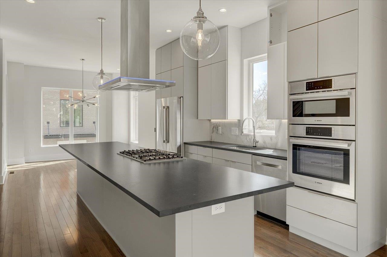 749 Willard Street, Unit 7 Durham, NC 27701 - Photo 7 of 43 a kitchen with kitchen island granite countertop a sink appliances and cabinets