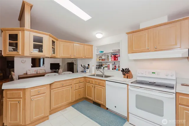a kitchen with a sink dishwasher and white cabinets with wooden floor