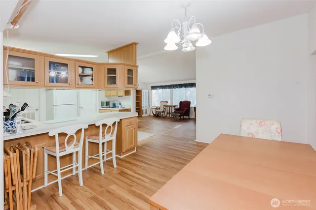 a dining room with wooden floor a chandelier a glass table and chairs