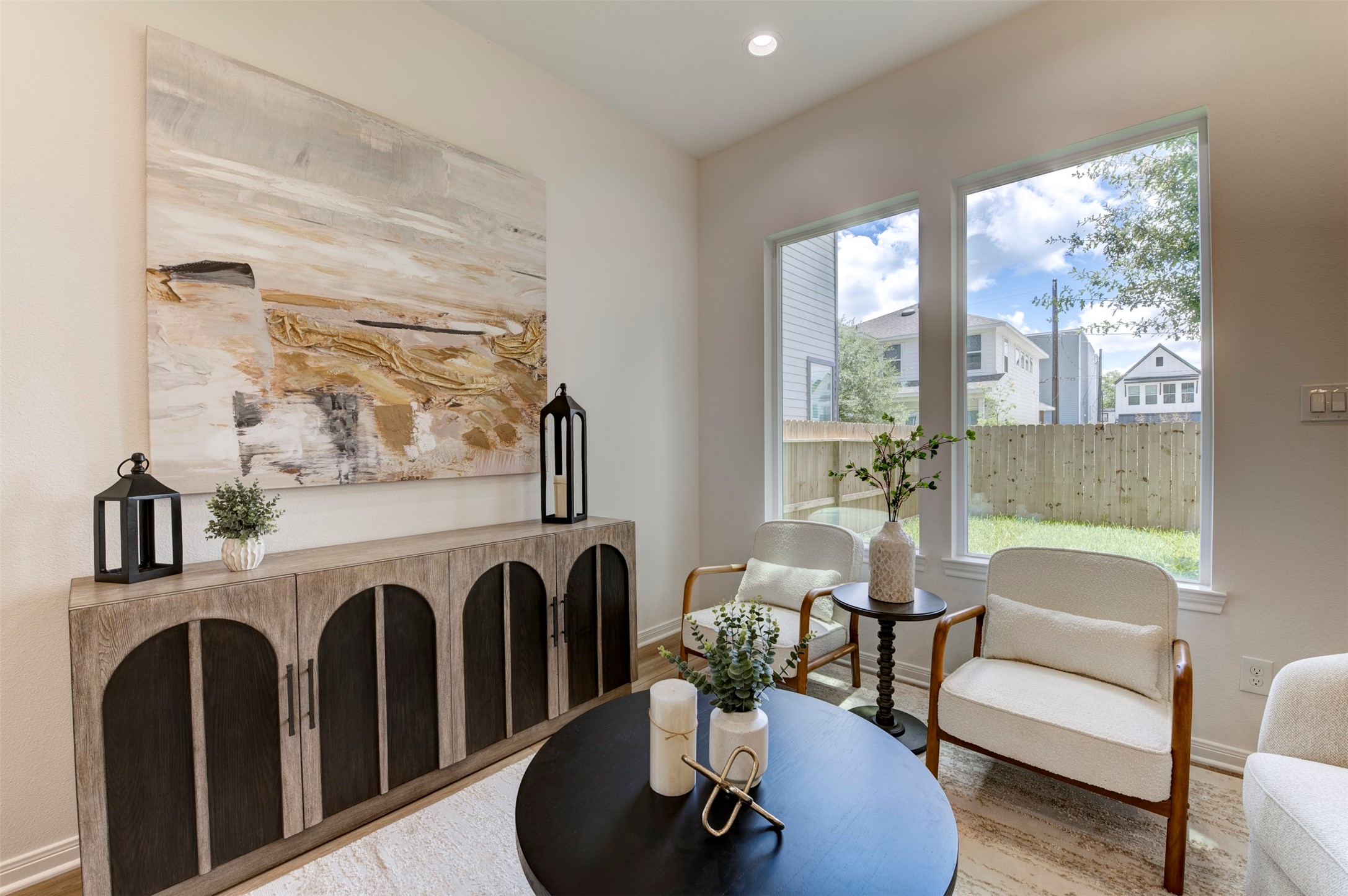 6807 Paris Street Houston, TX 77021 - Photo 12 of 50 Living room with hardwood floors, high ceilings, recessed lighting, matte black chandelier, floor-to-ceiling windows with backyard views, rear exit door, and open sightline to dining area.