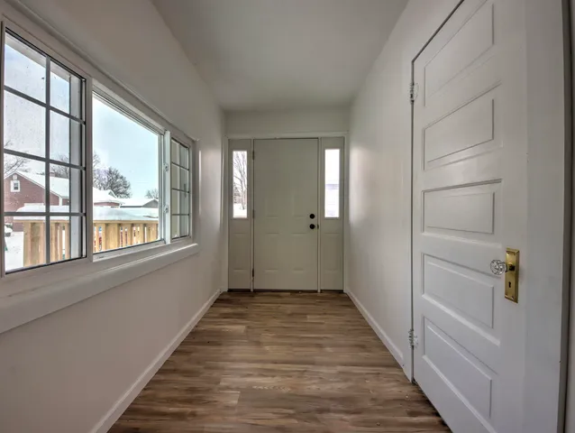 a view of a hallway with wooden floor and windows