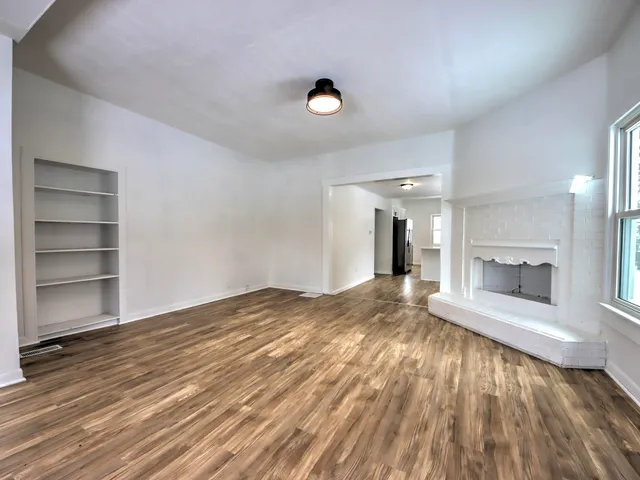 a view of empty room with wooden floor and fireplace
