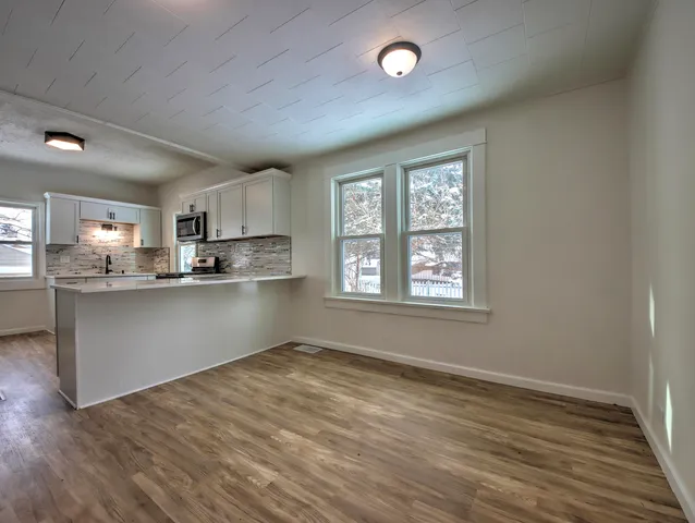 a kitchen with stainless steel appliances granite countertop a refrigerator a sink dishwasher a stove and white countertops with wooden floor