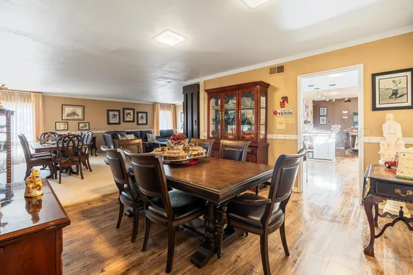 a view of a dining room and livingroom with furniture a rug a potted plant and a painting