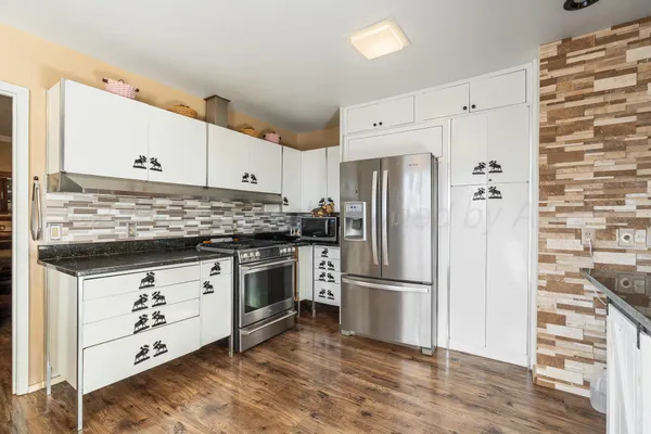 a kitchen with granite countertop a refrigerator sink and cabinets
