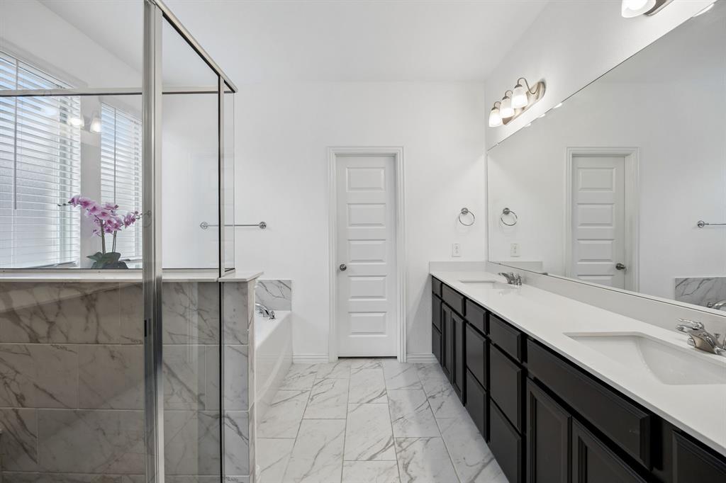 1303 Wheelwright Drive Forney, TX 75126 - Photo 23 of 39 Spacious bathroom featuring a glass-enclosed shower, a separate soaking tub, and a long double vanity with integrated sinks
