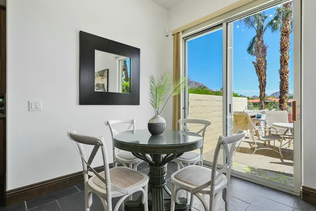 a view of a dining room with furniture one side kitchen view and wooden floor