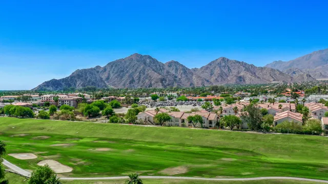 a view of a lush green field with mountains in the background