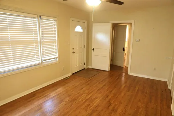 an empty room with wooden floor and windows