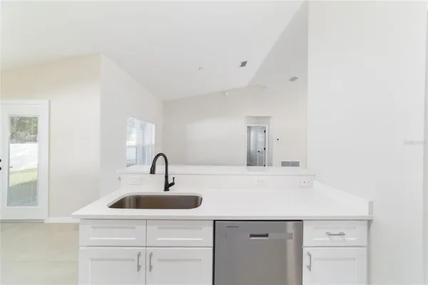 an empty room with windows and refrigerator