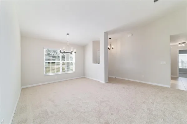 an empty room with windows and chandelier fan