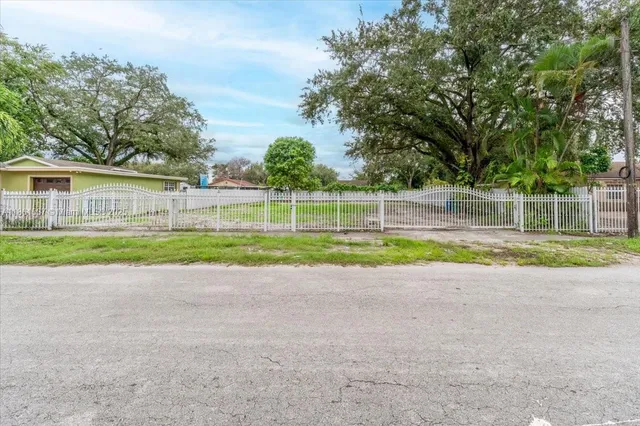 a view of a house with a big yard and palm trees