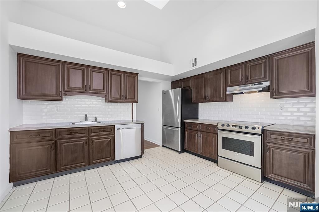 850 Main Street, Unit 306 Hackensack, NJ 07601 - Photo 4 of 8 a kitchen with stainless steel appliances granite countertop a stove top oven sink and cabinets