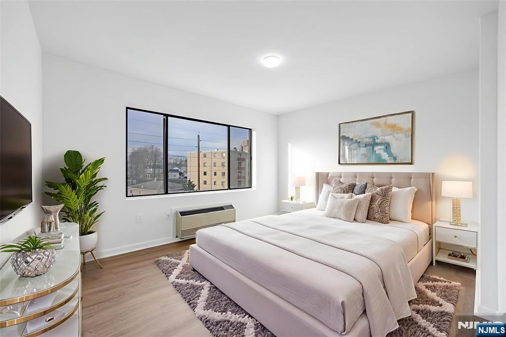 850 Main Street, Unit 306 Hackensack, NJ 07601 - Photo 6 of 8 a bedroom with a large bed and a potted plant