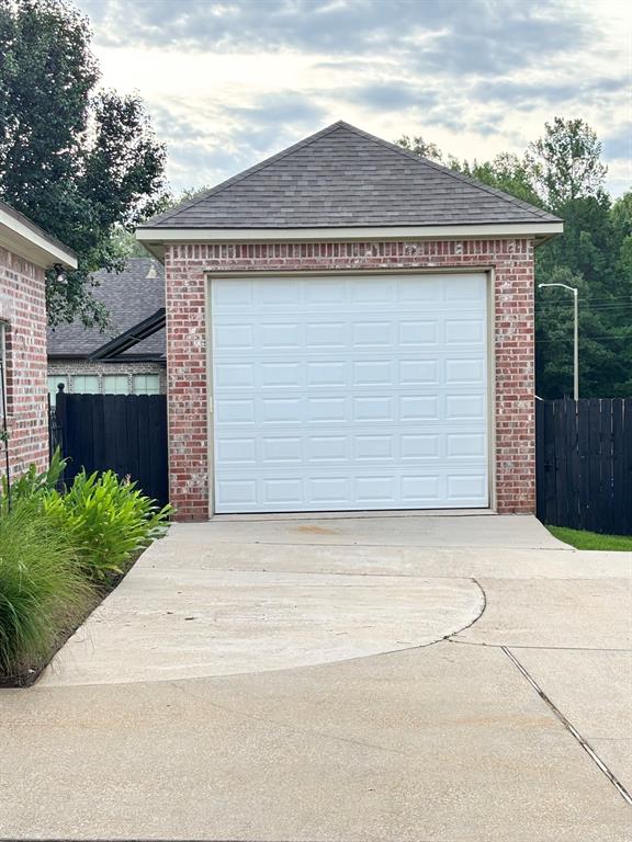 605 Jade Haughton, LA 71037 - Photo 31 of 34 Brick exterior garage with a white panel door, a sloped roof with shingle tiles, and a concrete driveway