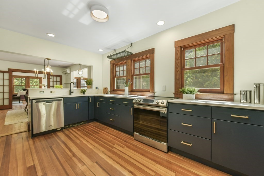 46 Spring Street, Unit 2 Somerville, MA 02143 - Photo 4 of 22 a kitchen with stainless steel appliances kitchen island granite countertop a sink cabinets and wooden floor
