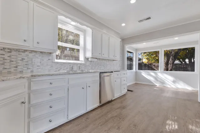 a kitchen with granite countertop white cabinets white appliances and a wide window
