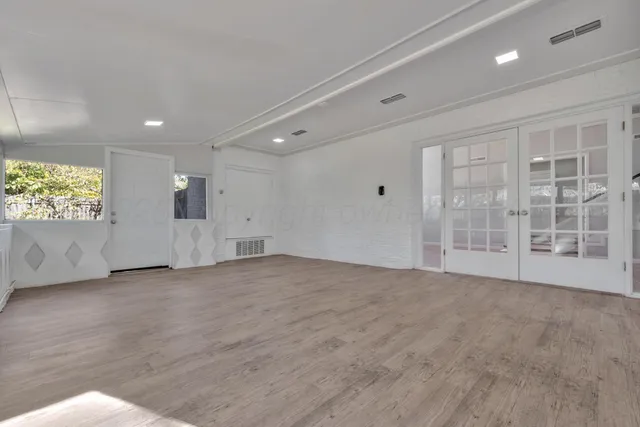 an empty room with wooden floor and windows