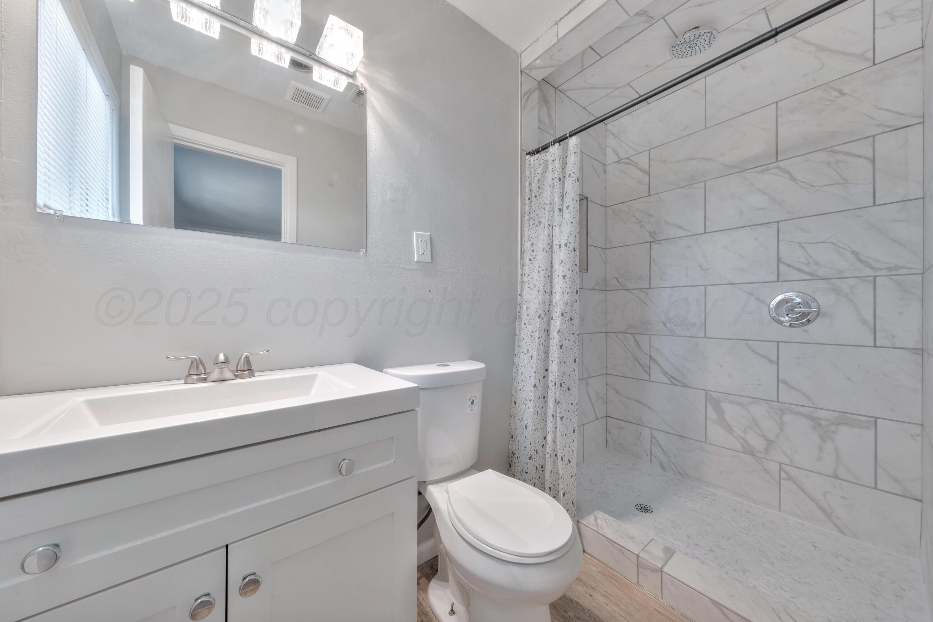 3700 Paramount Boulevard Amarillo, TX 79109 - Photo 25 of 40 a bathroom with a sink a toilet and a mirror