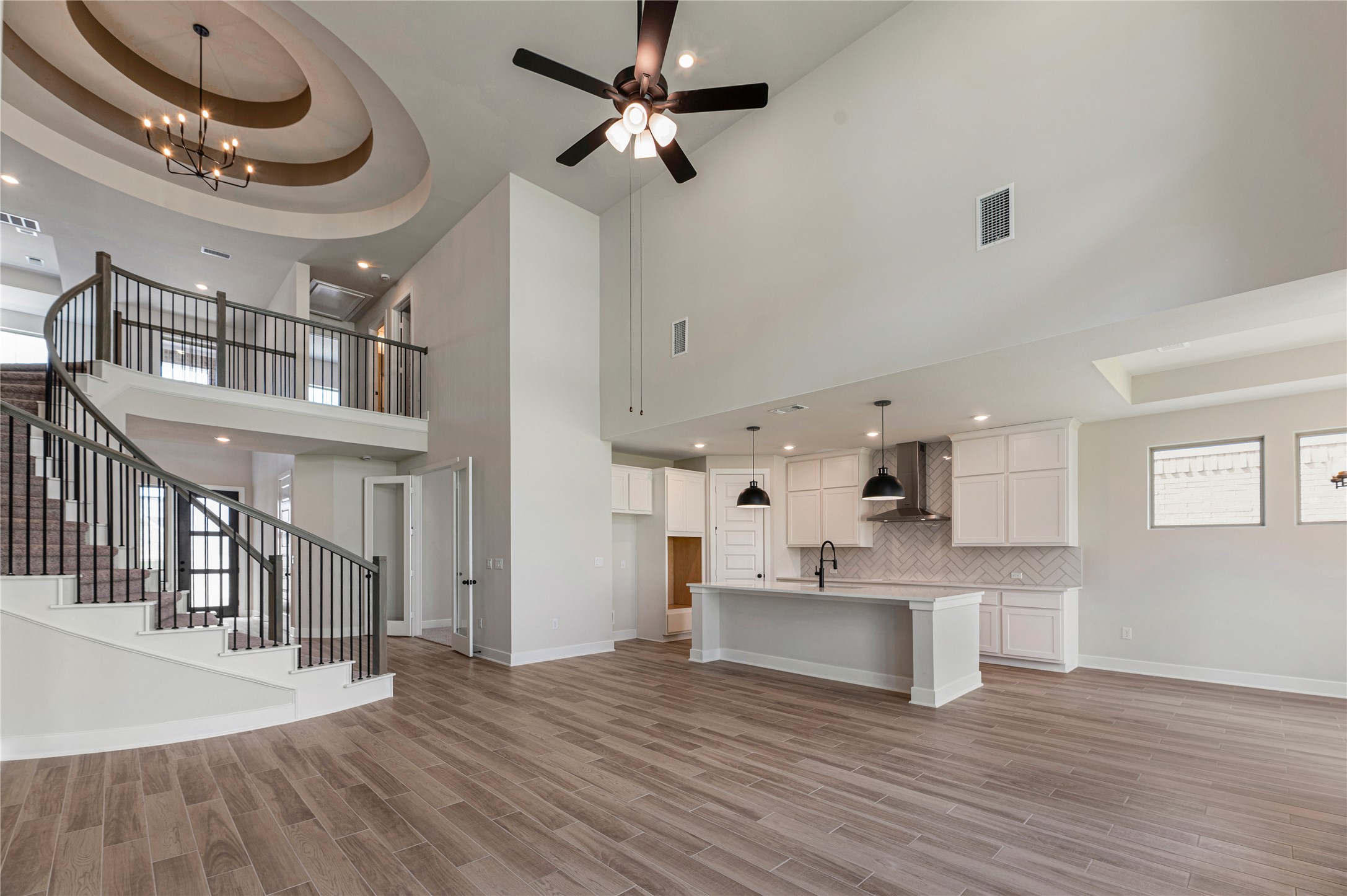 1508 Rodeo Ridge Drive Georgetown, TX 78628 - Photo 4 of 37 Unfurnished living room with a tray ceiling, recessed lighting, a towering ceiling, a chandelier, and stairway