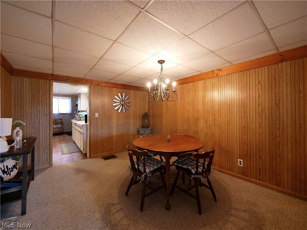 75450 Fair Road Freeport, OH 43973 - Photo 43 of 45 Carpeted dining room with an inviting chandelier, a paneled ceiling, and wooden walls