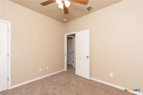an empty room with a chandelier fan and a ceiling fan