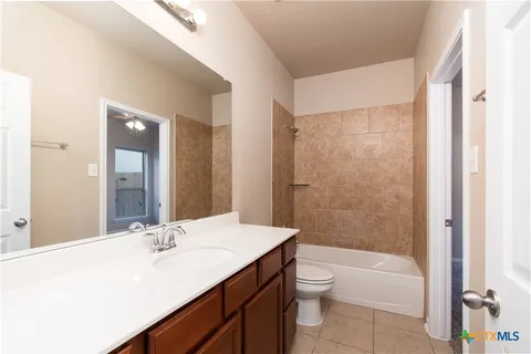 a bathroom with a bathtub shower sink vanity mirror and toilet