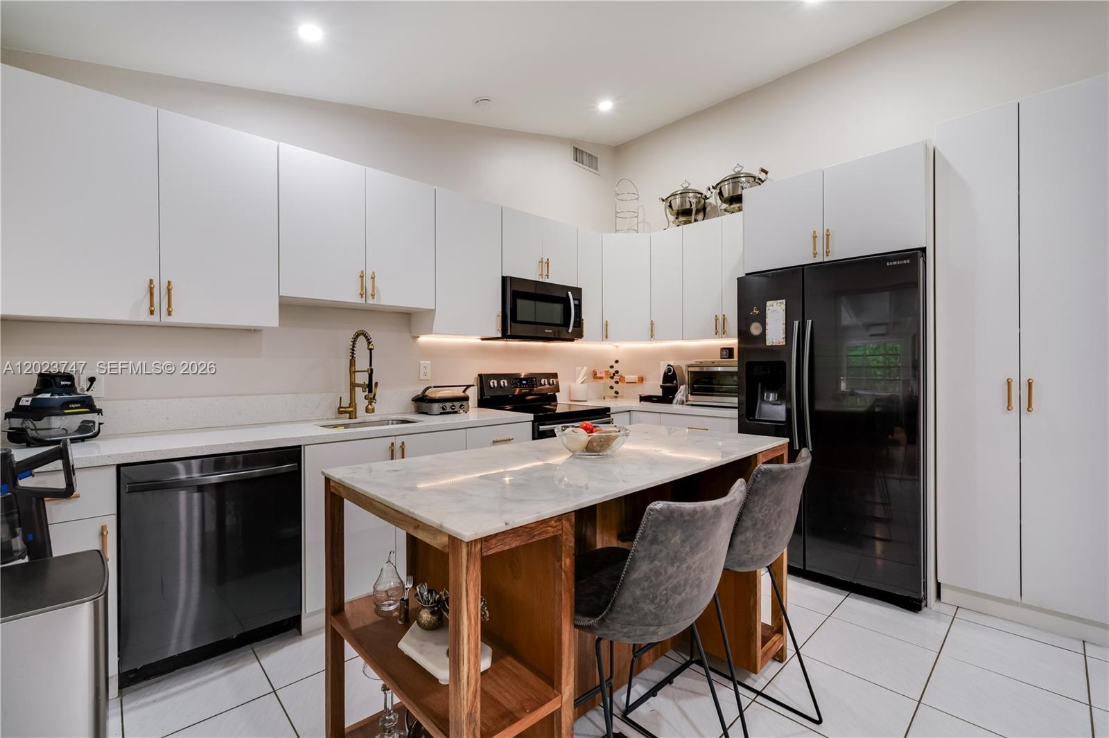 11515 Southwest 81st Road, Unit 11515 Pinecrest, FL 33156 - Photo 9 of 33 a kitchen with stainless steel appliances a stove a refrigerator a sink a stove a dining table and chairs