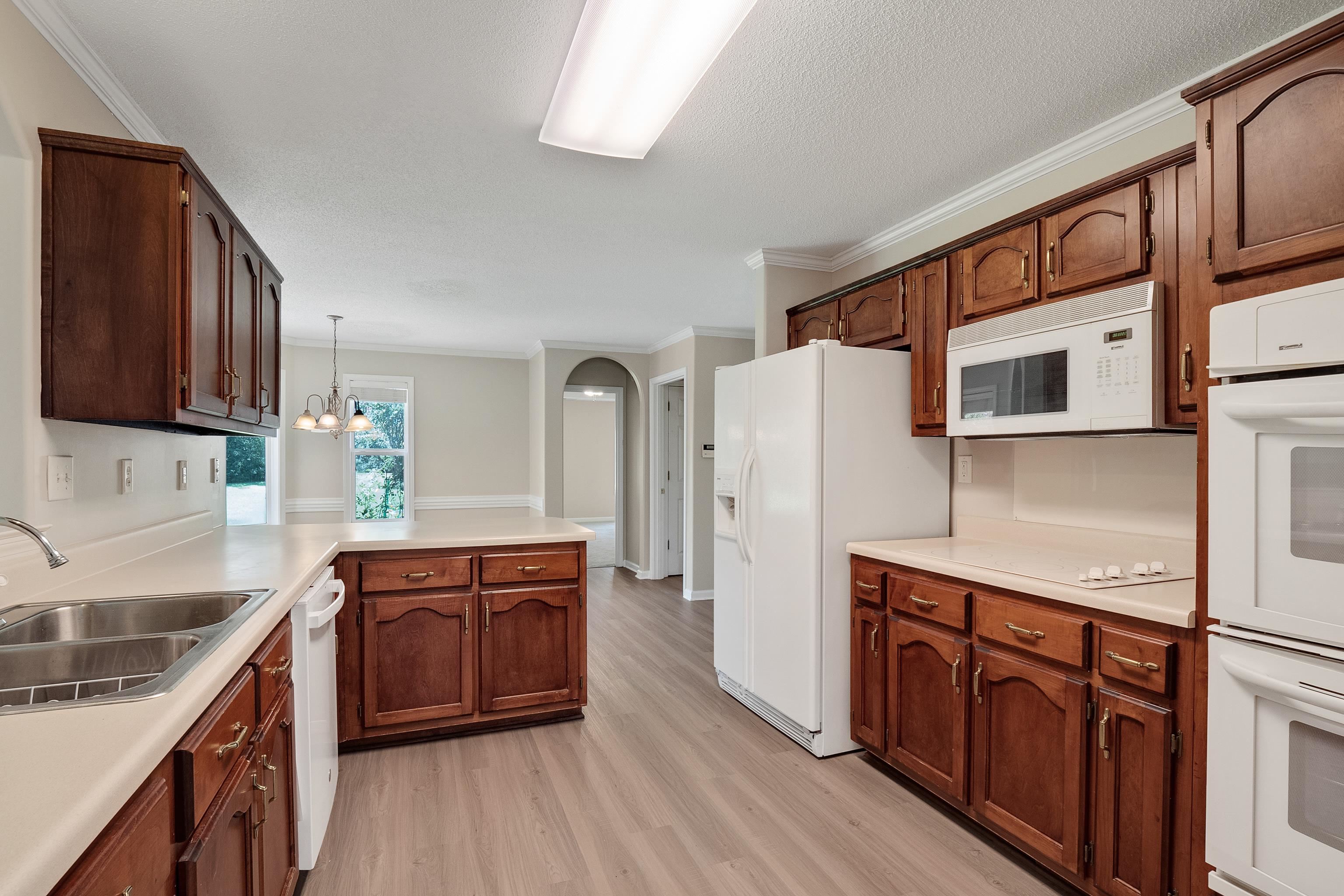 1171 Macon Hall Road Cordova, TN 38018 - Photo 9 of 35 a kitchen with stainless steel appliances granite countertop a refrigerator a sink dishwasher and wooden cabinets with wooden floor