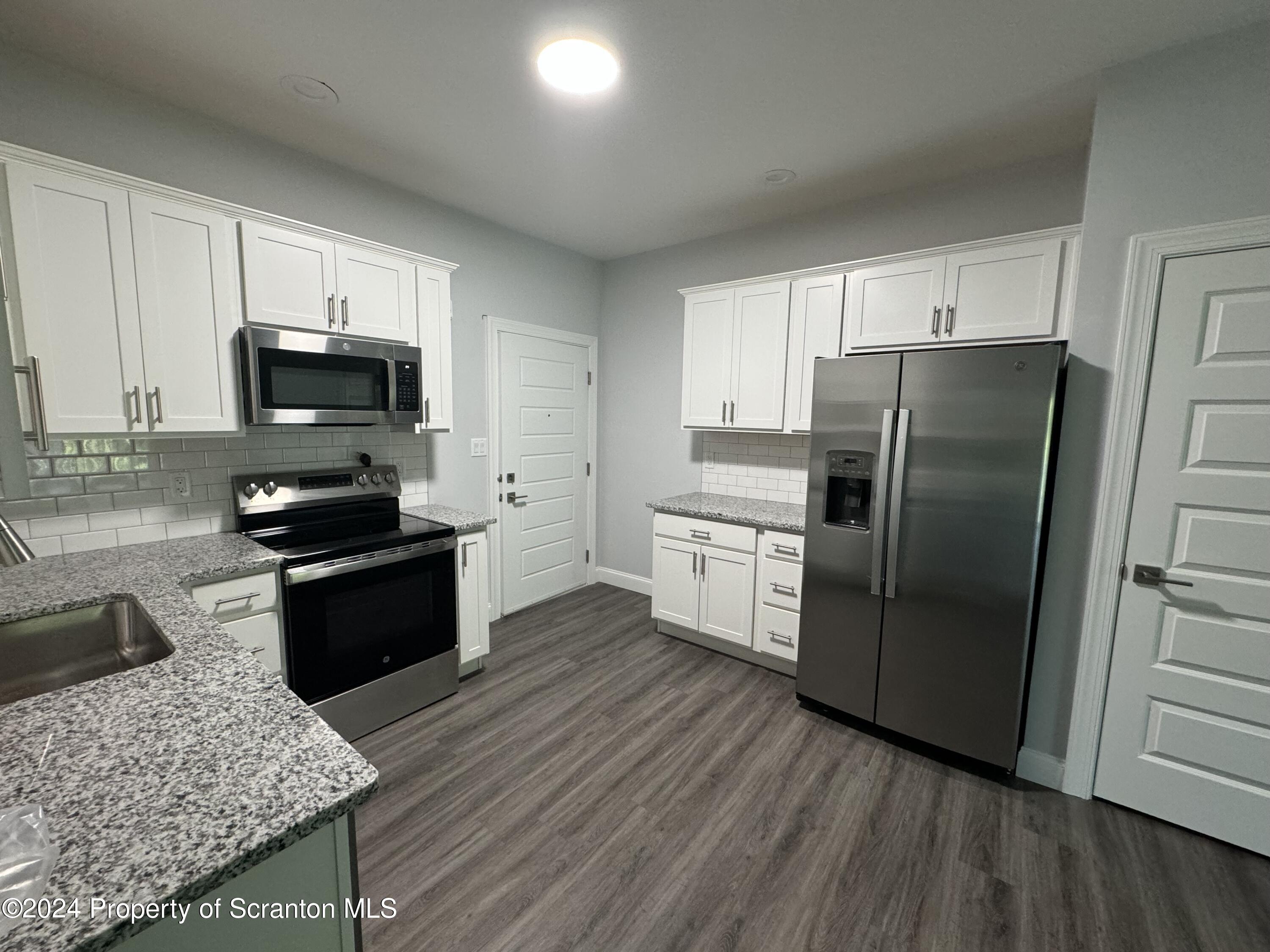 104 Circle Drive Taylor, PA 18517 - Photo 6 of 31 a kitchen with granite countertop a refrigerator and a stove top oven
