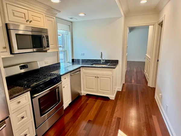 a kitchen with stainless steel appliances kitchen island granite countertop wooden floors and a sink