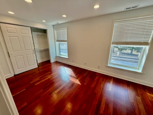 an empty room with wooden floor and windows