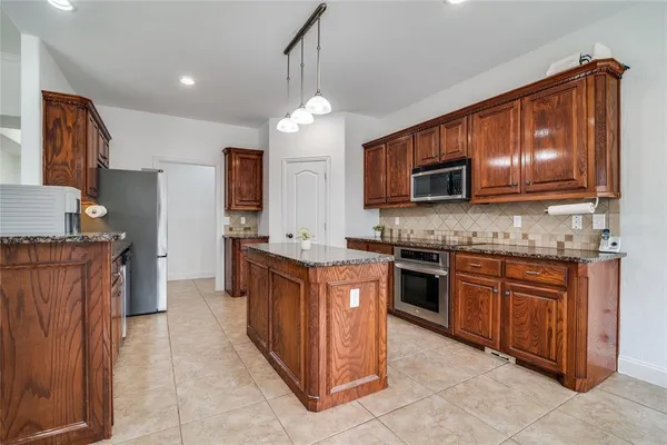 a kitchen with stainless steel appliances granite countertop wooden cabinets a stove top oven a sink and dishwasher