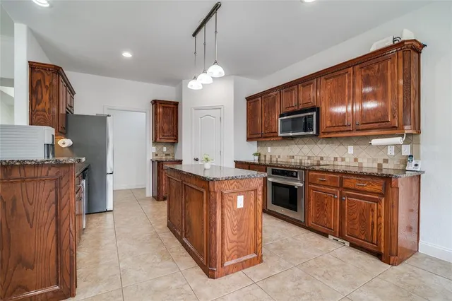 a kitchen with stainless steel appliances granite countertop wooden cabinets a stove top oven a sink and dishwasher