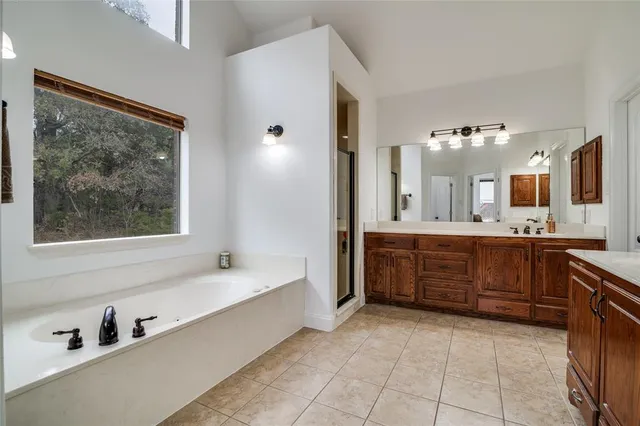 a spacious bathroom with a tub sink and mirror