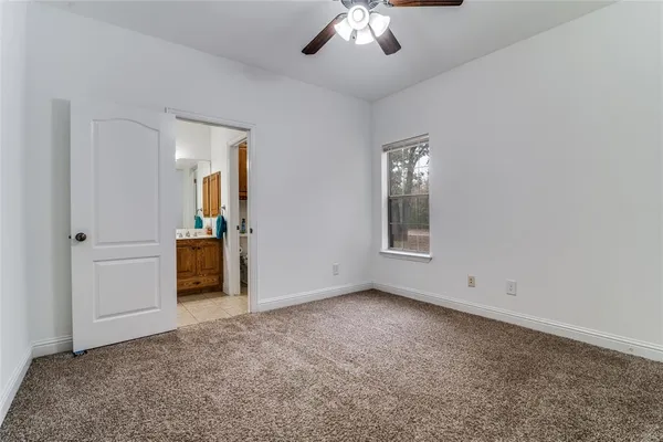 an empty room with chandelier fan and windows