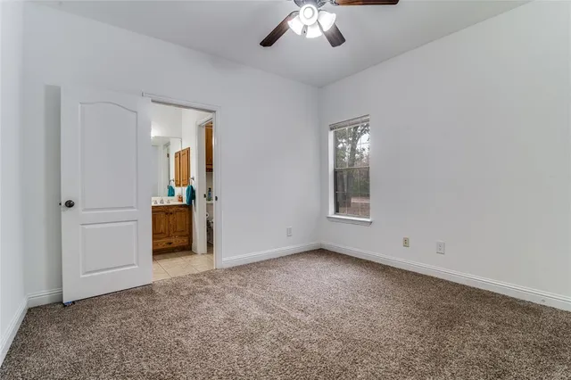 an empty room with chandelier fan and windows