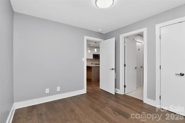 a view of an empty room with wooden floor and closet