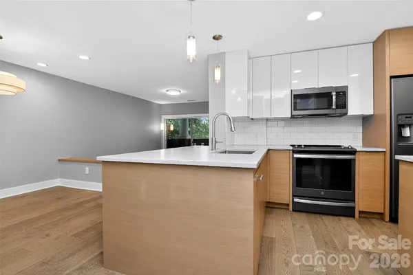 a kitchen with stainless steel appliances a stove a microwave a sink and cabinets