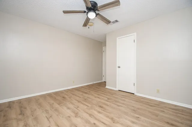an empty room with a window and a ceiling fan