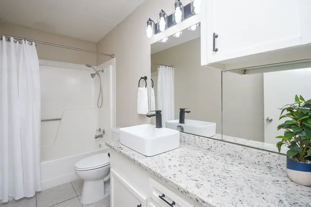 a bathroom with a granite countertop sink a toilet and shower