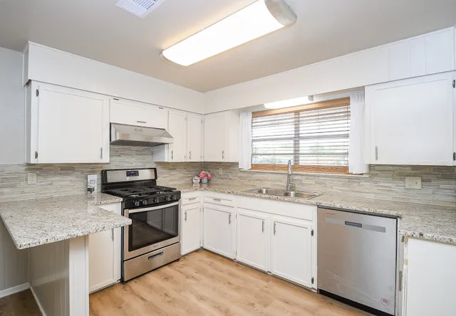 a kitchen with stainless steel appliances granite countertop a sink stove and cabinets