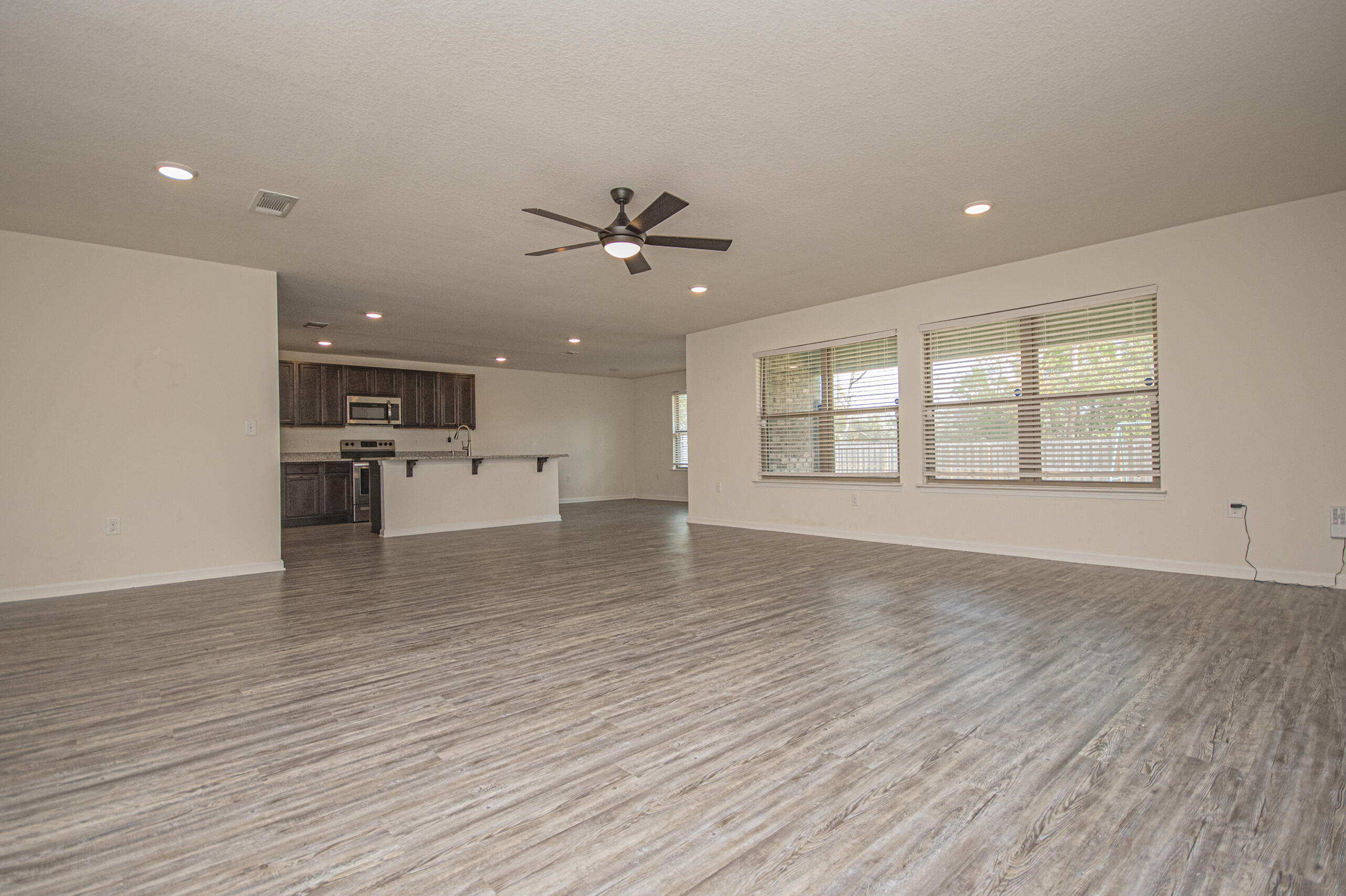 356 Merlin Court Crestview, FL 32539 - Photo 19 of 70 a view of an empty room with a kitchen and wooden floor