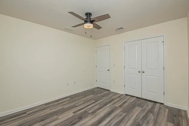 an empty room with wooden floor and windows