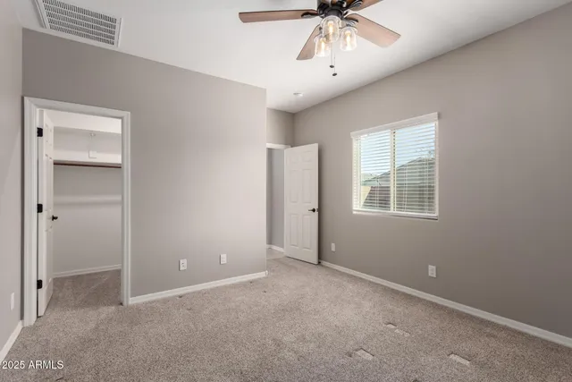 an empty room with a chandelier fan and windows