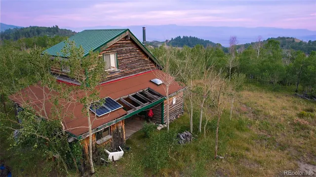 an aerial view of a house with a yard and mountain view in back