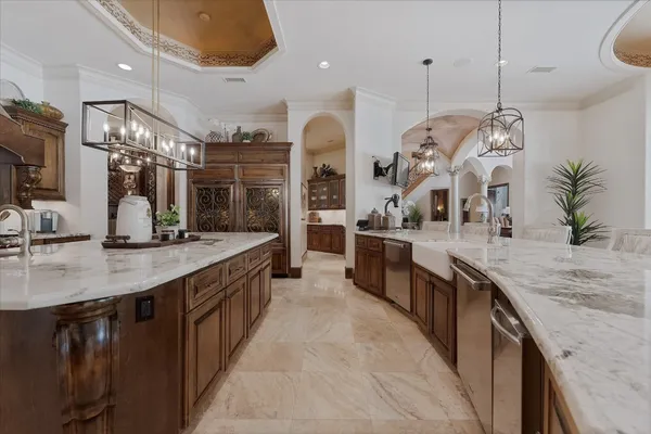 a large kitchen with a large counter top a sink and stainless steel appliances