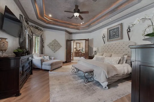 a spacious bedroom with a bed a couch and a flat tv screen on the dresser