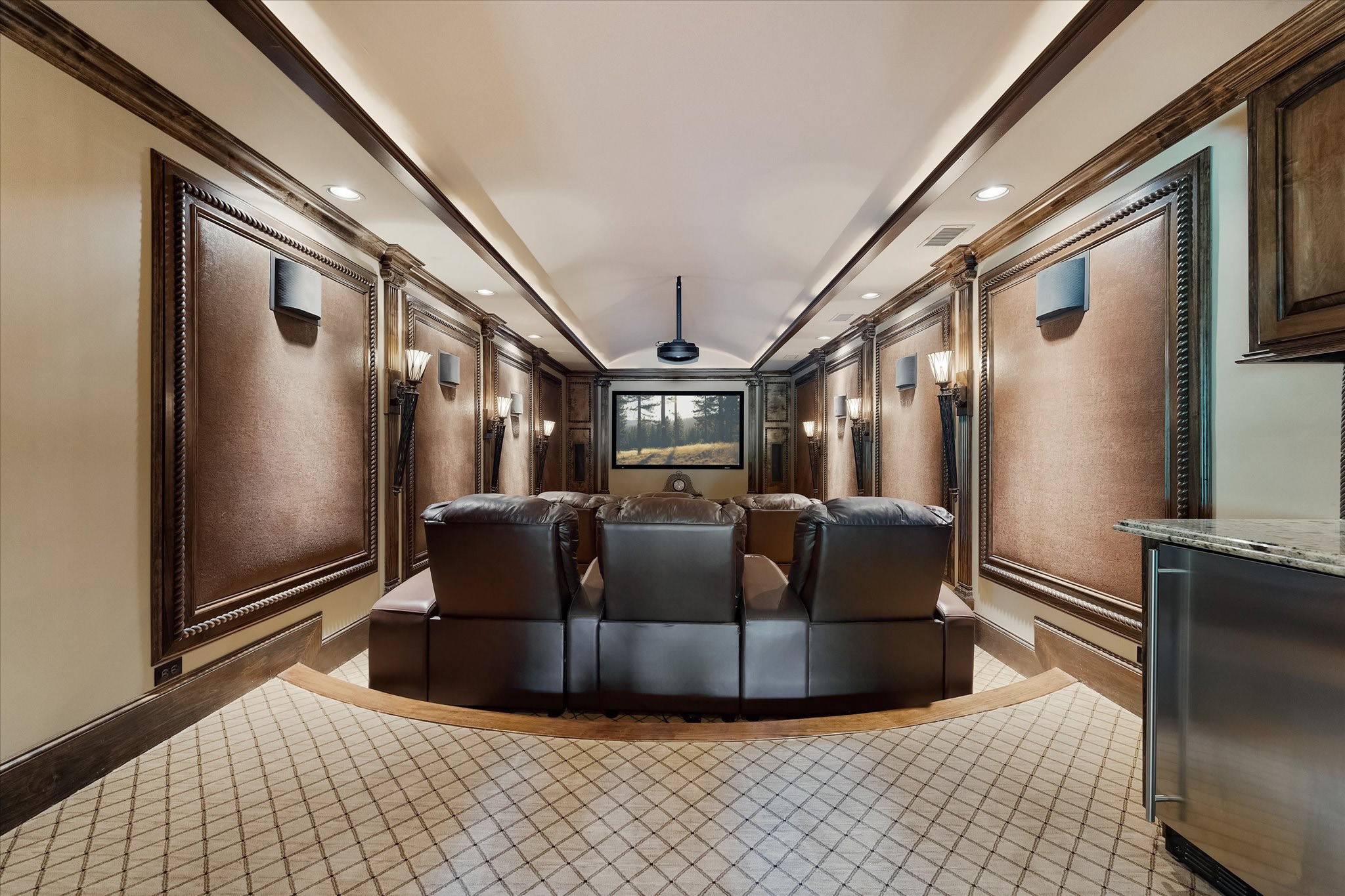 28322 Meadow Forest Magnolia, TX 77355 - Photo 27 of 50 The theater room, located above the garage with sound deadening decorative panels. features nine electrical adjustable seats arranged in a stadium seating configuration. Built-in beverage cooler & Microwave, built-in projector screen, projector, and surround sound system. Custom millwork & crown molding, Designer carpet flooring with hardwood leading edges along with barrel ceiling controlled recessed & tray cove lighting, & sconce torch lighting enhances the ambiance.