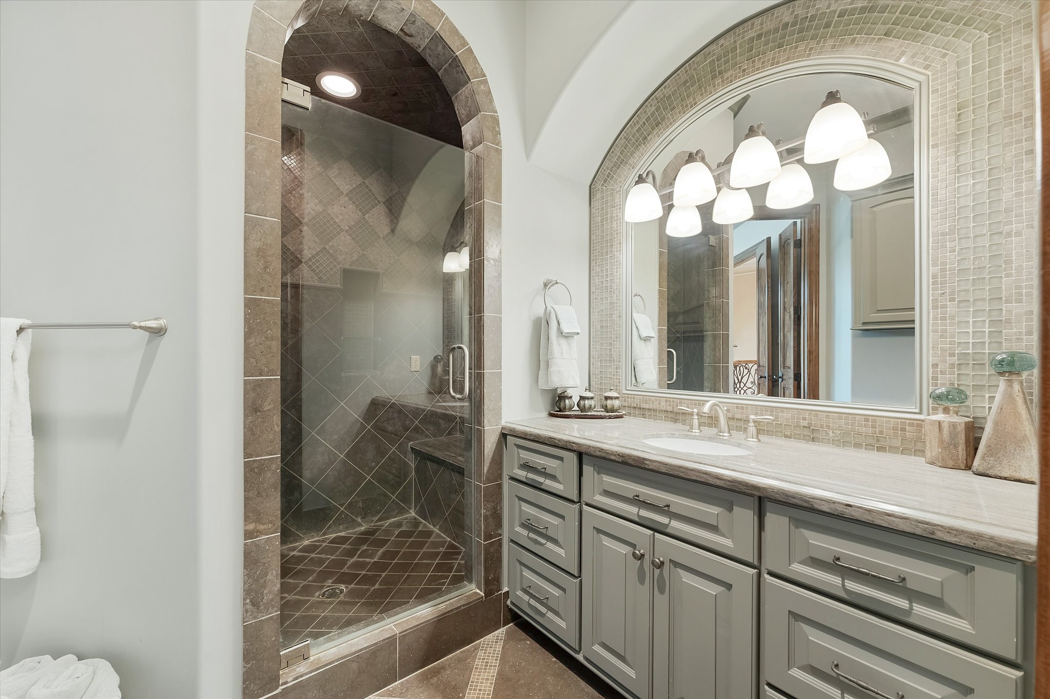 28322 Meadow Forest Magnolia, TX 77355 - Photo 34 of 50 Guest bedroom ensuite #2 on the second floor. Dual Adler wood doors lead to the Ensuite with custom tile flooring with an intricate pattern and a shower with a built-in bench. Granite countertop vanity with Custom framed mirror. Walk-in Closet With Built-ins and Door Jamb Light Switch.
